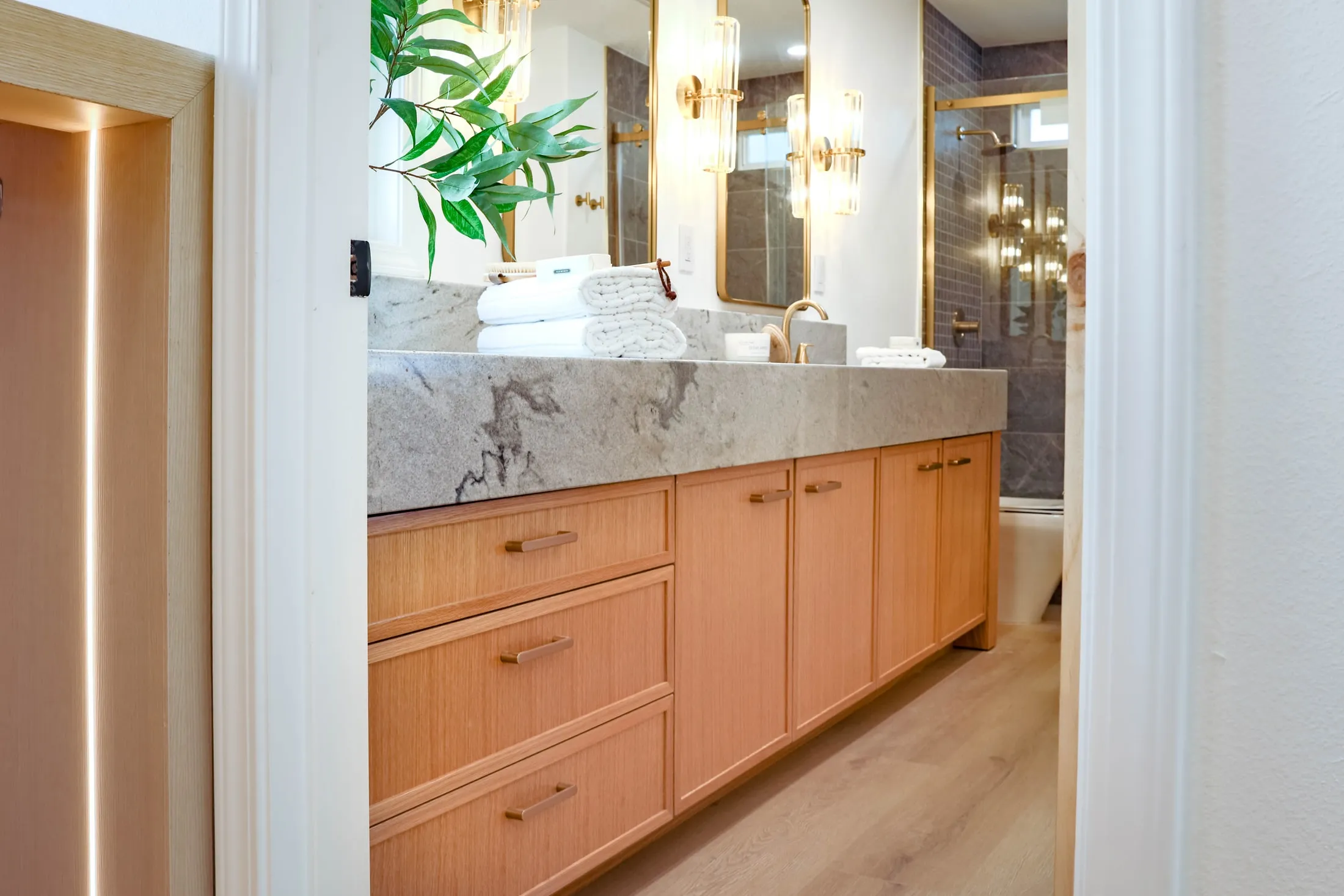Custom oak bathroom vanity beneath a stone countertop and wall mirrors