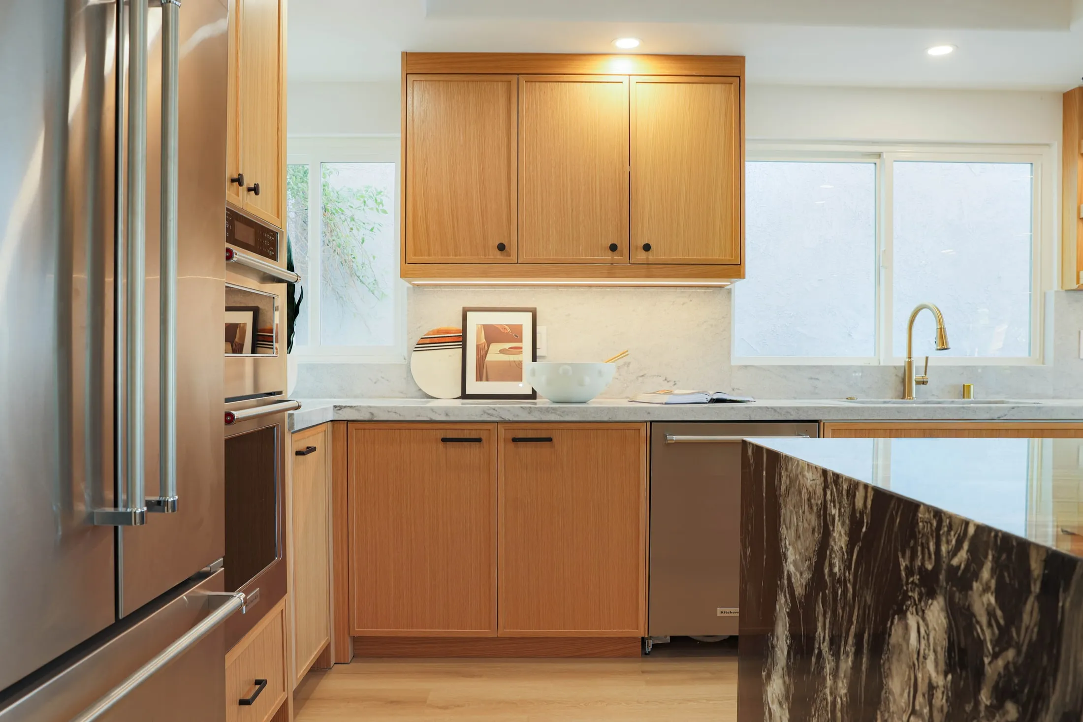 Custom kitchen cabinetry beside a stone island and stainless steel appliances
