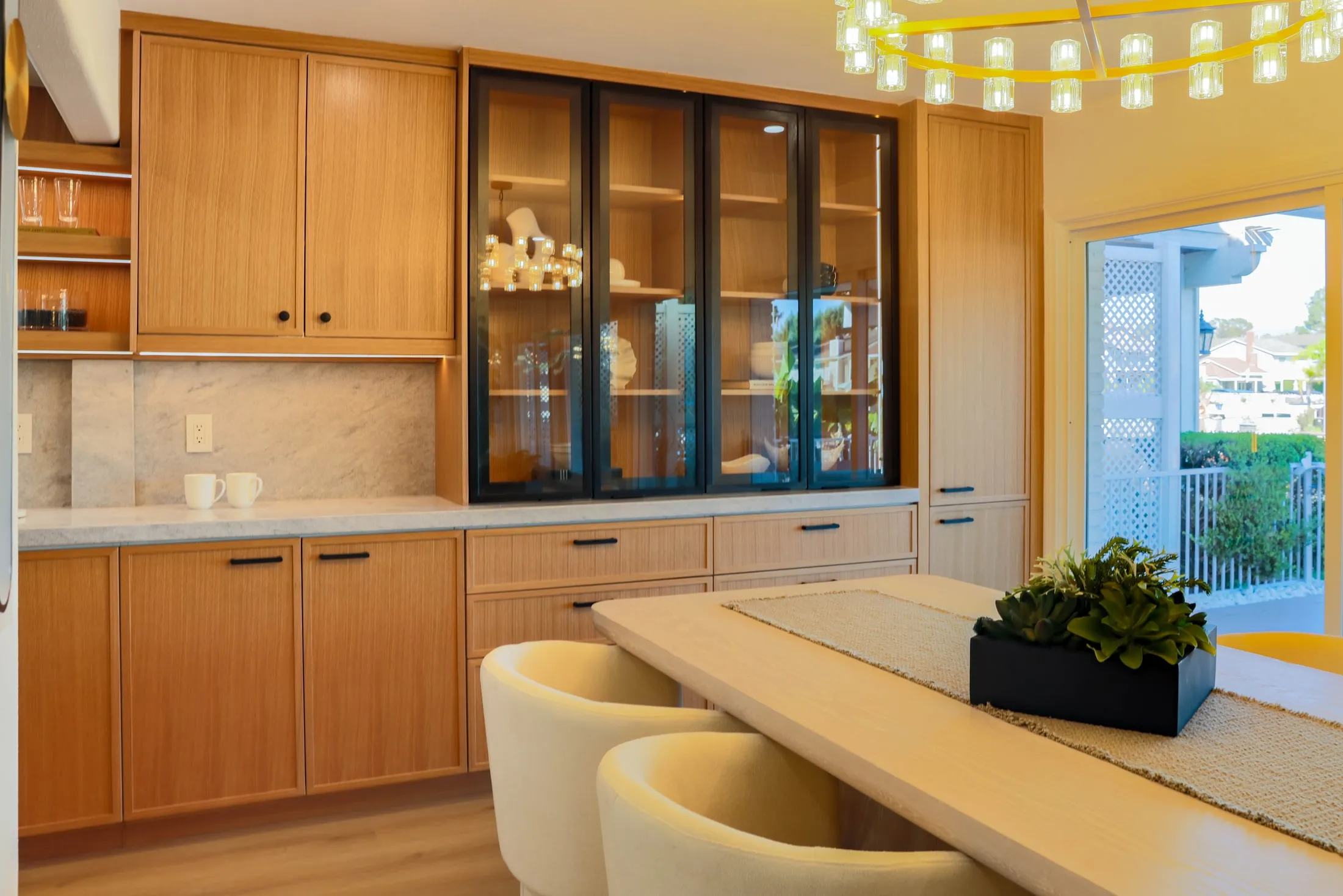 Glass-front bar cabinetry with integrated lighting beside the dining area