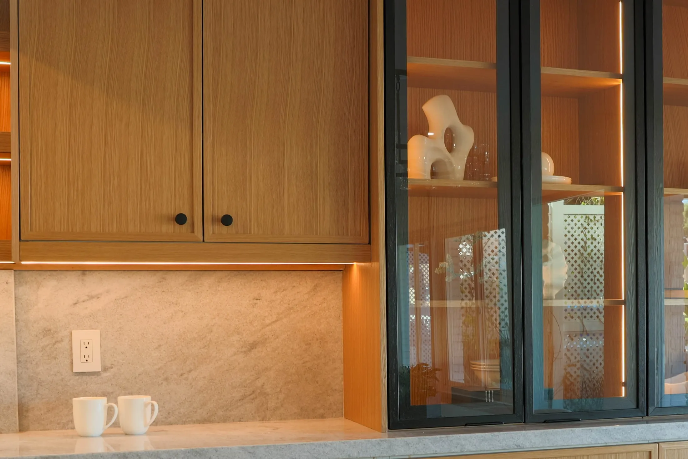 Kitchen display cabinet with glass doors, open shelves, and warm lighting